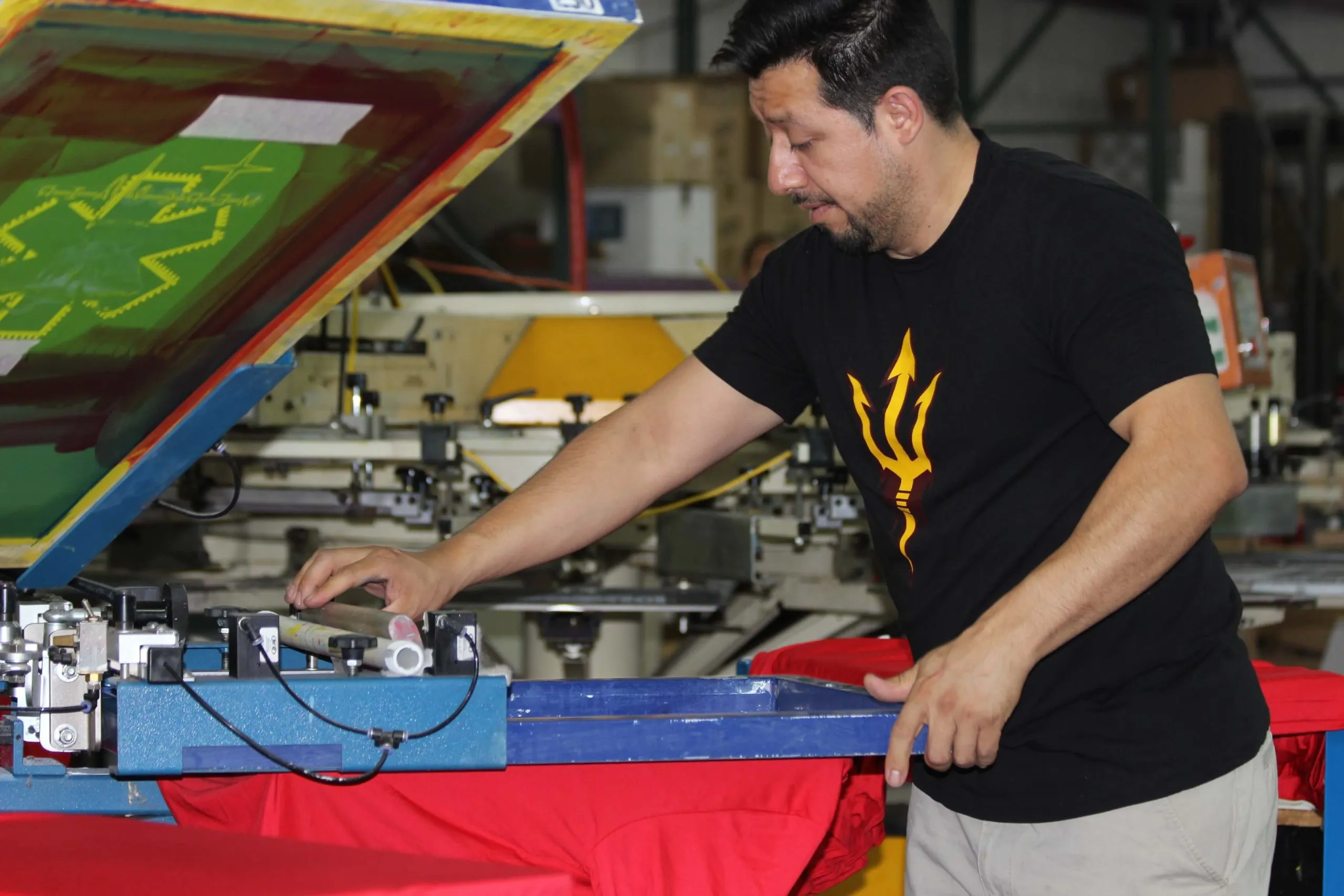 EZ Print Source team member operating a manual screen printing press